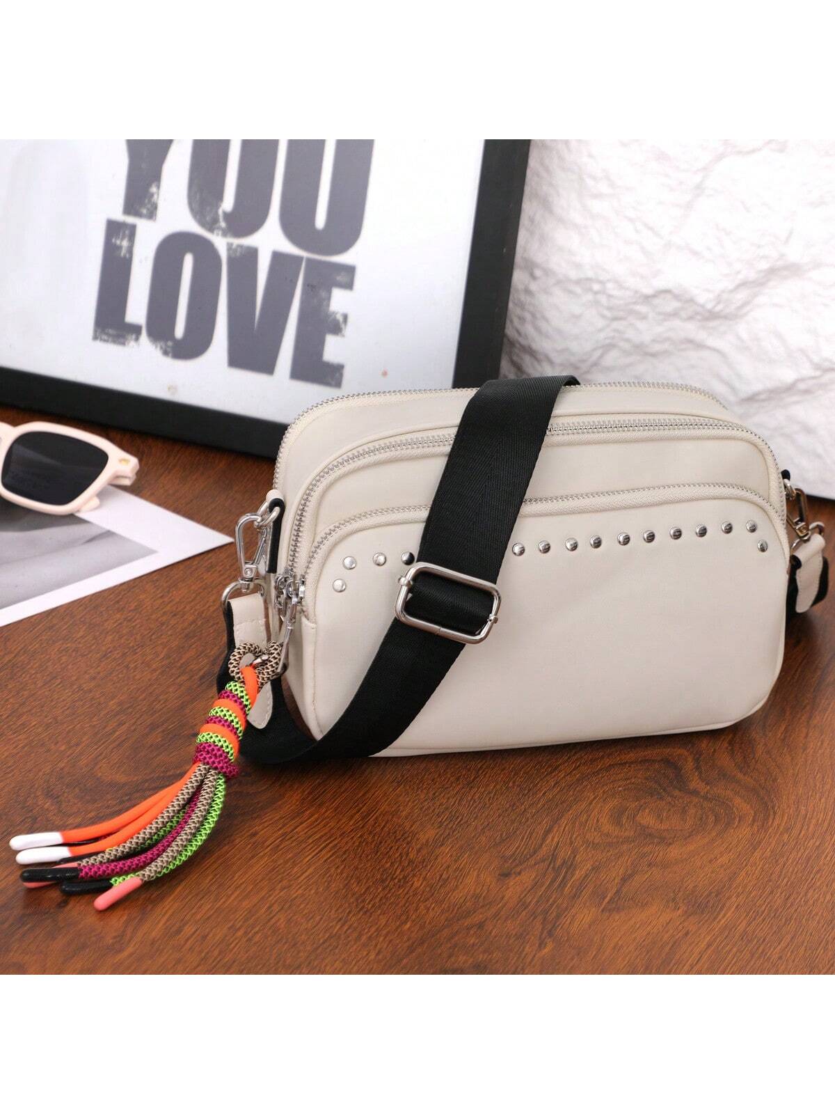 Bolso bandolera pequeño para mujer, color beige, con múltiples bolsillos, borla moderna, compacto y organizado. Bolso cuadrado negro con correa ancha y cómoda de nailon tipo guitarra.