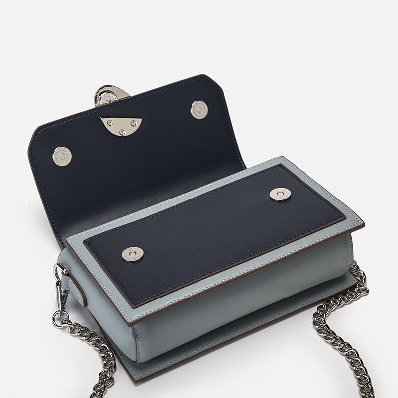 Bolso bandolera pequeño de piel auténtica con múltiples bolsillos y tono contrastante.