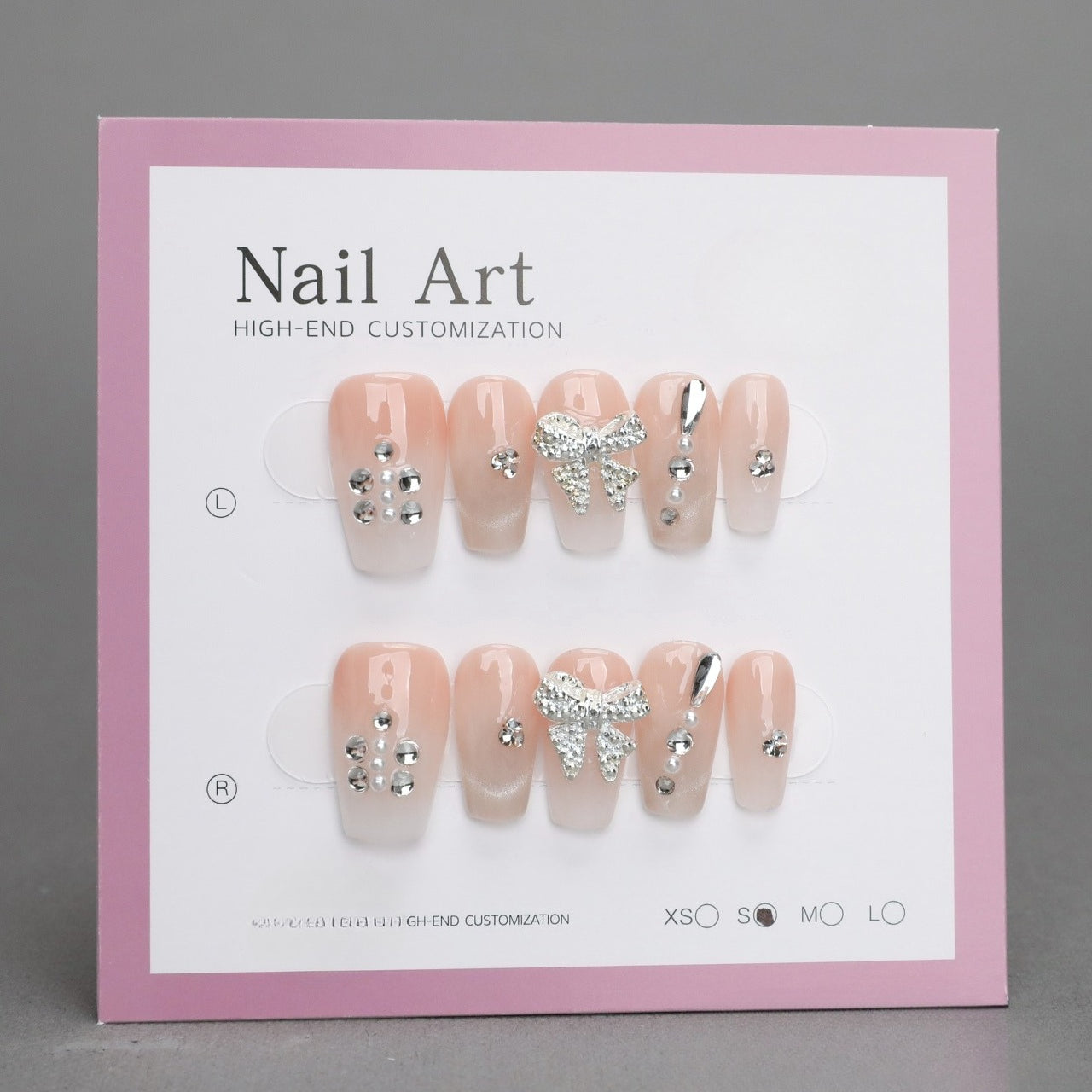 Nail art display with decorative nails on a pink and white card.