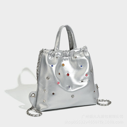 Mochila versátil de gran capacidad, estilo bandolera con cadena y asa de mano. 