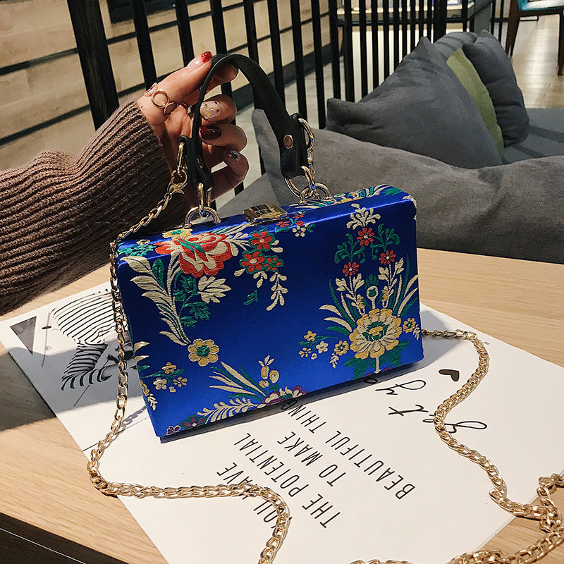 Bolso de mano tipo clutch con estampado floral, ideal para bodas y eventos especiales. Elegante diseño en tonos antiguos. 