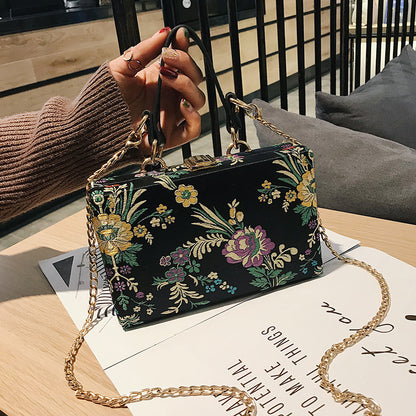 Bolso de mano tipo clutch con estampado floral, ideal para bodas y eventos especiales. Elegante diseño en tonos antiguos. 
