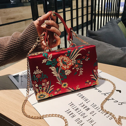 Bolso de mano tipo clutch con estampado floral, ideal para bodas y eventos especiales. Elegante diseño en tonos antiguos. 