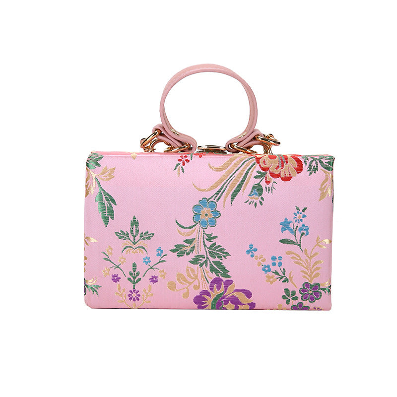 Bolso de mano tipo clutch con estampado floral, ideal para bodas y eventos especiales. Elegante diseño en tonos antiguos. 