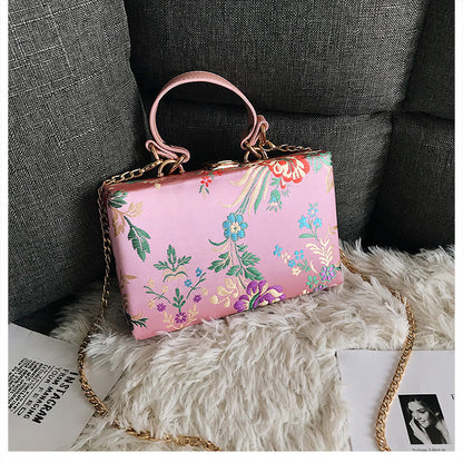 Bolso de mano tipo clutch con estampado floral, ideal para bodas y eventos especiales. Elegante diseño en tonos antiguos. 